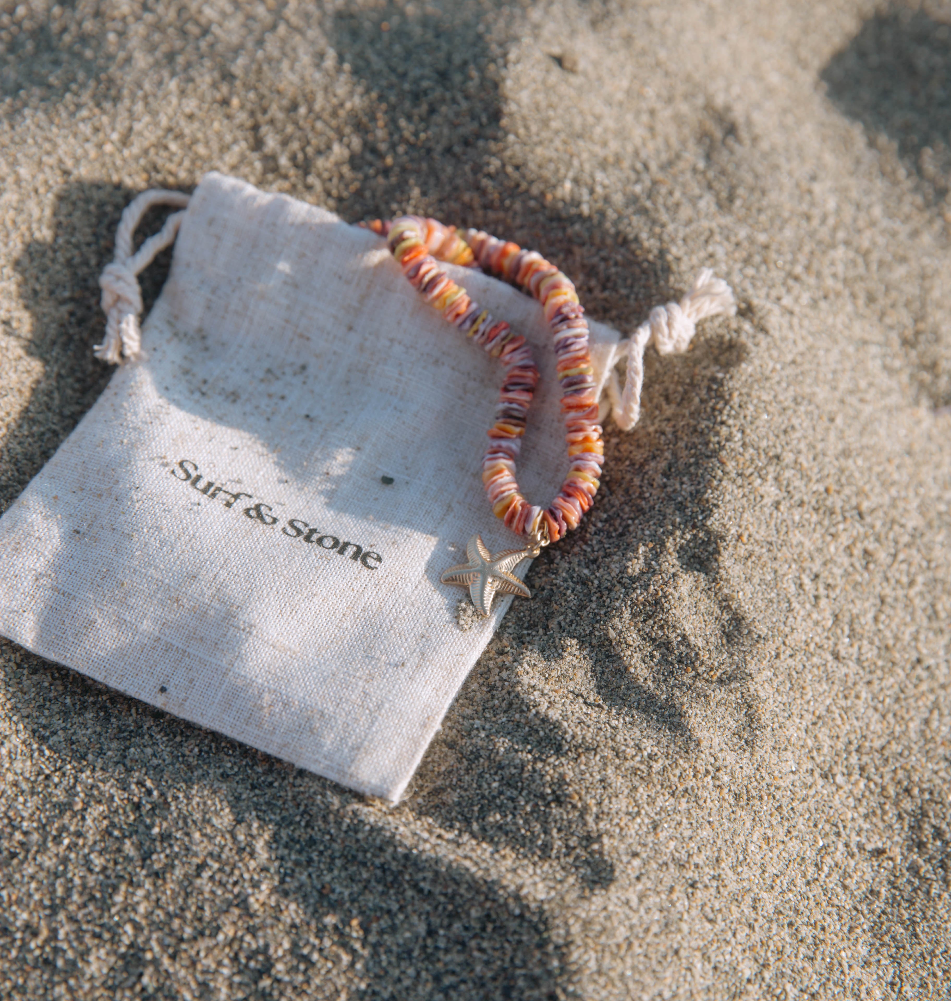 Beaded bracelet on a branded drawstring bag on sandy surface